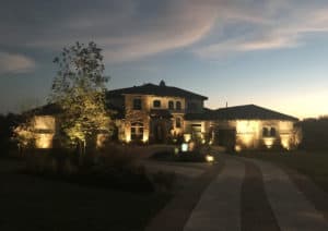 A home's exterior seen lit up by well designed landscape lighting