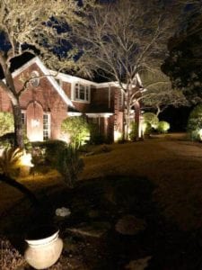 front yard of a home lit up by exterior lighting