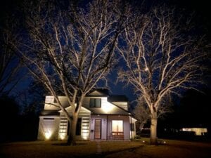 white wooden home lit up with landscape lighting