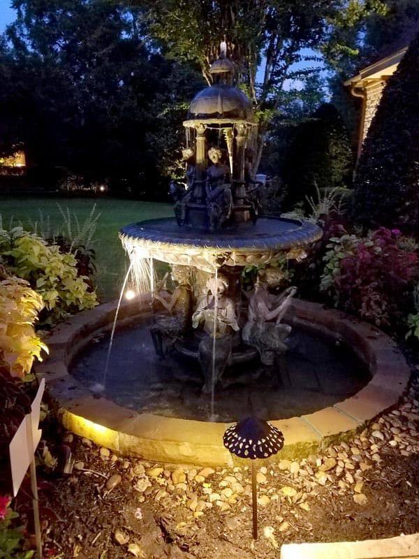 water fountain in a garden lit up with outdoor lighting