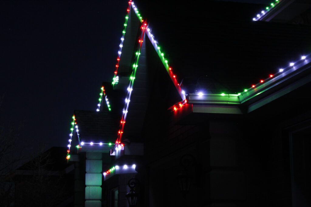 A night time side view of permanent Christmas lights installed on a roofline.